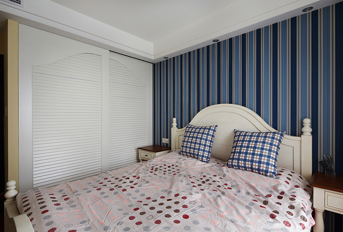 卧室背景以蓝色和藏青的条纹式来表现彩色的层次鲜明，枕头也与墙面互相呼应，白色的衣柜显得光线更加明亮。
