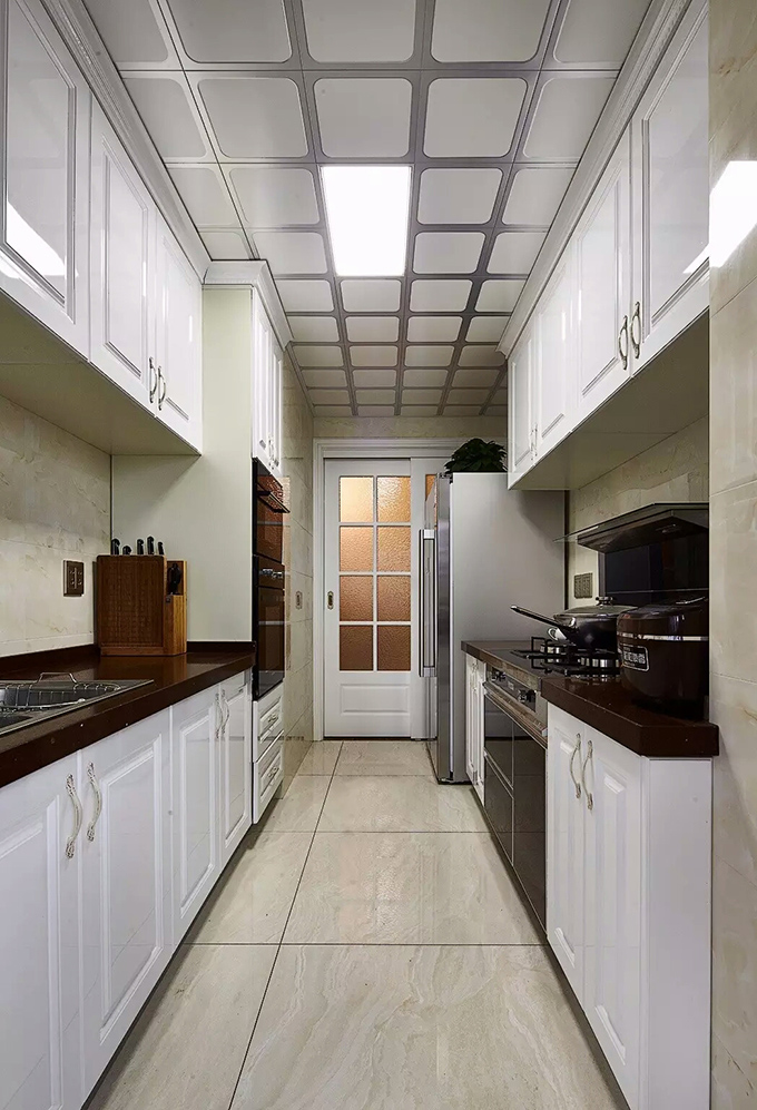 长方体的厨房采用了两面橱柜的形式突显增大空间面积，白色橱柜与地砖互相呼应再配上黑色灶面体现厨房清扫容易。