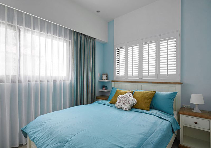 白色的天花板与蓝色的墙体的相撞突出空间优雅，灰色的窗帘与木质百叶窗对应体现设计风格，棕色与蓝色床上用制造晚霞海浪。
