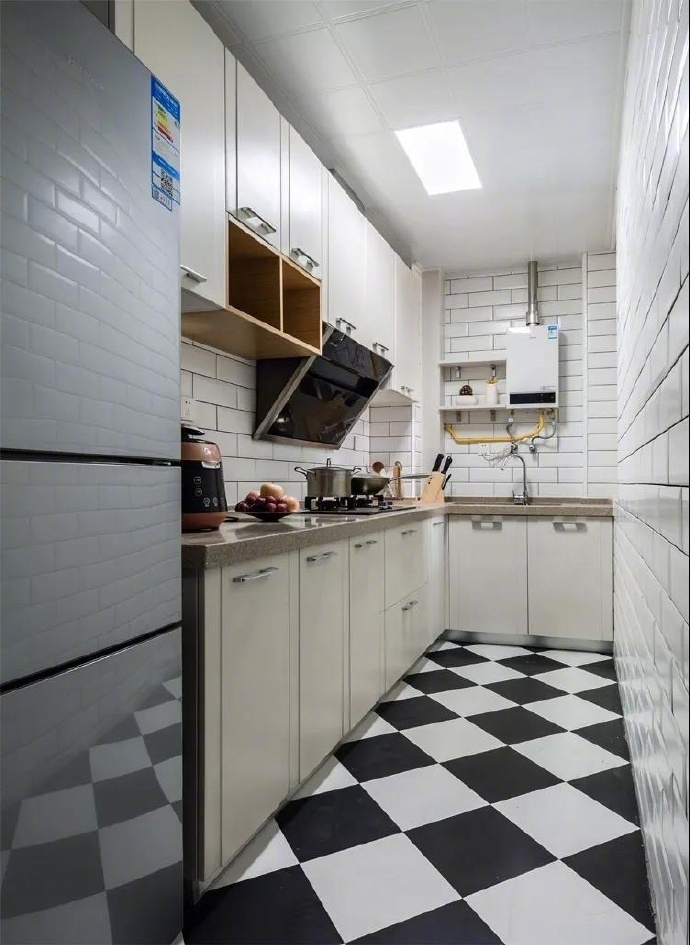 厨房的设计也是简单的黑白灰色为主，地面的黑白色方砖的瓷砖，给空间一种强调的作用，也是一种装饰的作用，墙面的小白瓷砖的铺贴，使空间看上去更加的开阔。
